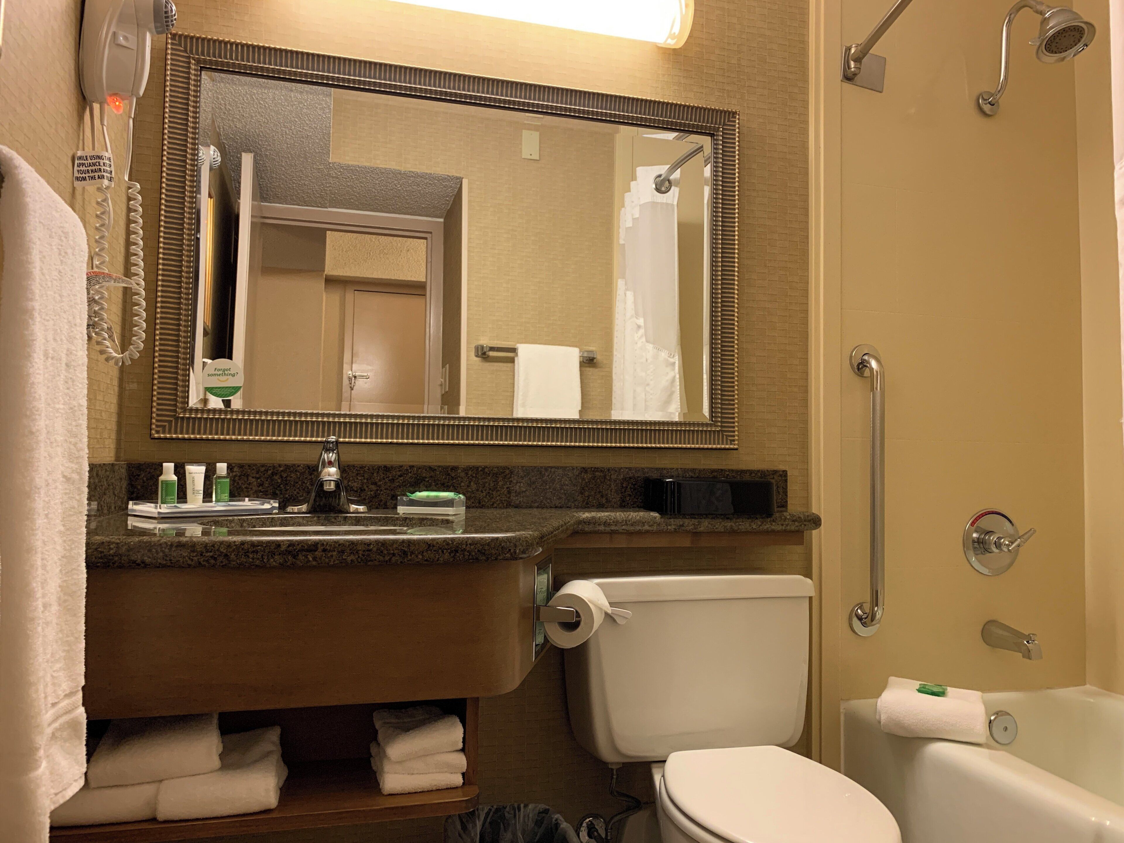 A bathroom with a sink, mirror, toilet, and shower.