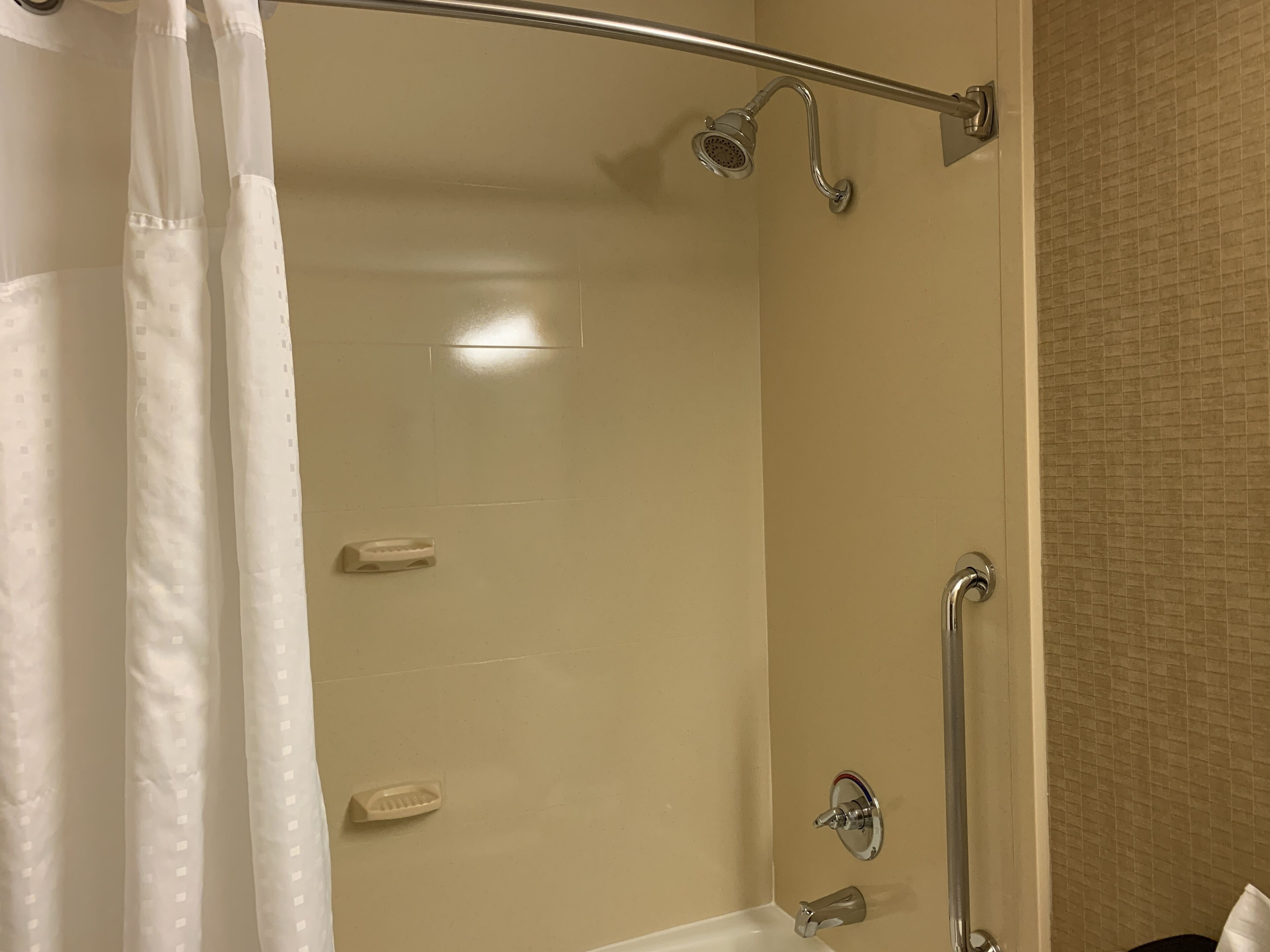 A shower area with a glass door, a handheld showerhead, a handheld showerhead, and a handheld showerhead.