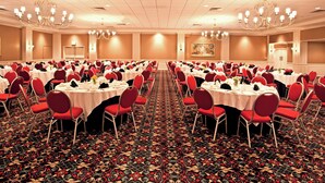 A banquet hall with round tables, red chairs, chandeliers, and a patterned carpet. - Holiday Inn Johnstown Downtown by IHG (Johnstown)