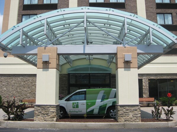 A Holiday Inn hotel entrance with a covered walkway and a green and white shuttle service. - Holiday Inn Johnstown Downtown by IHG (Johnstown)