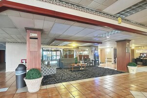 A lobby with a reception desk, seating area, and a trash bin.
