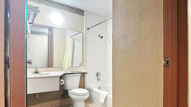 Une salle de bain comprenant des toilettes, un lavabo, un miroir et une baignoire.