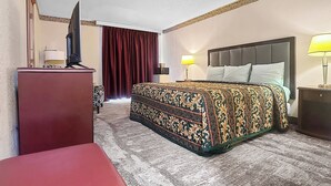 Habitación de hotel con cama, escritorio, televisor y dos lámparas.