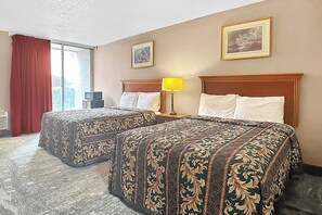 Una habitación de hotel con dos camas, un escritorio, una lámpara y una ventana con cortinas.