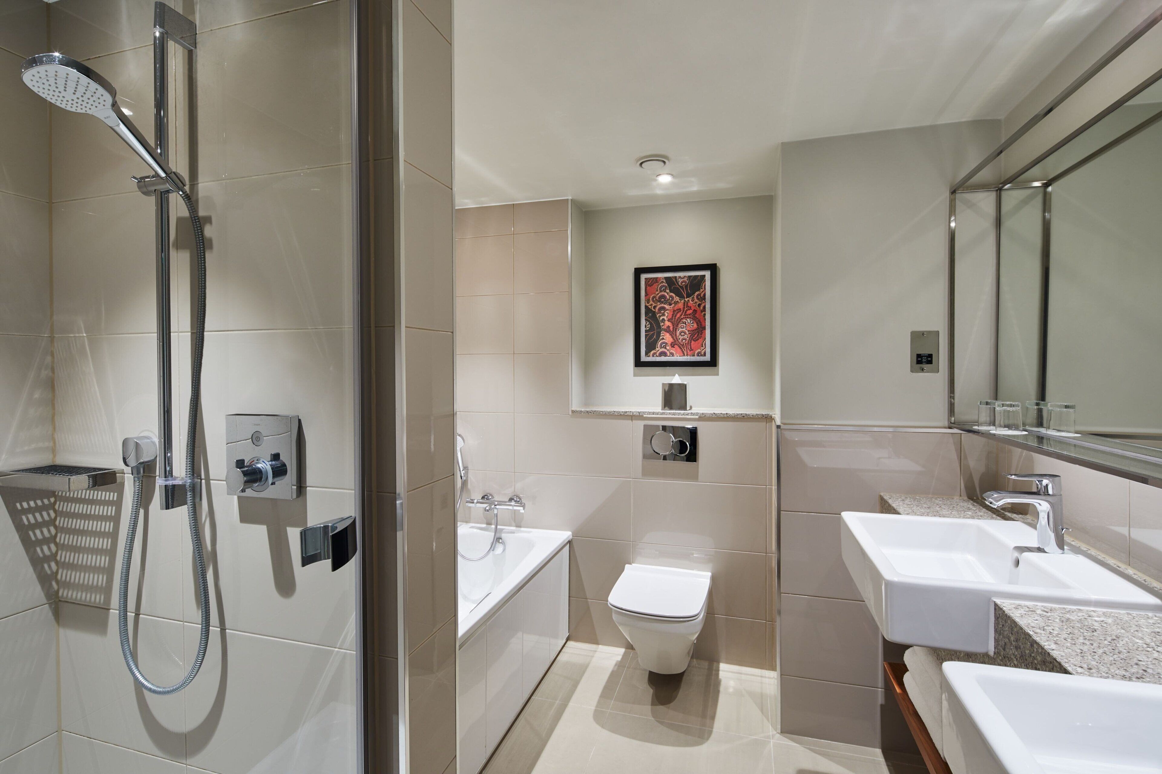 A modern bathroom with a shower, toilet, and two sinks.