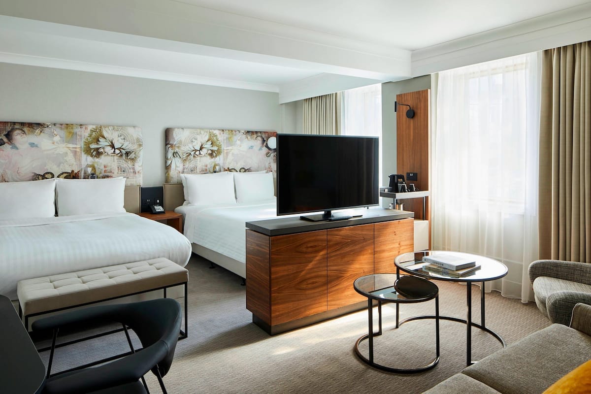 A hotel room with a bed, a TV, a desk, a chair, and a sofa.