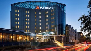 A modern Marriott hotel with a glass facade, a visible entrance, and a nearby Cast Iron Bar & Grill. - London Marriott Hotel Kensington (London)