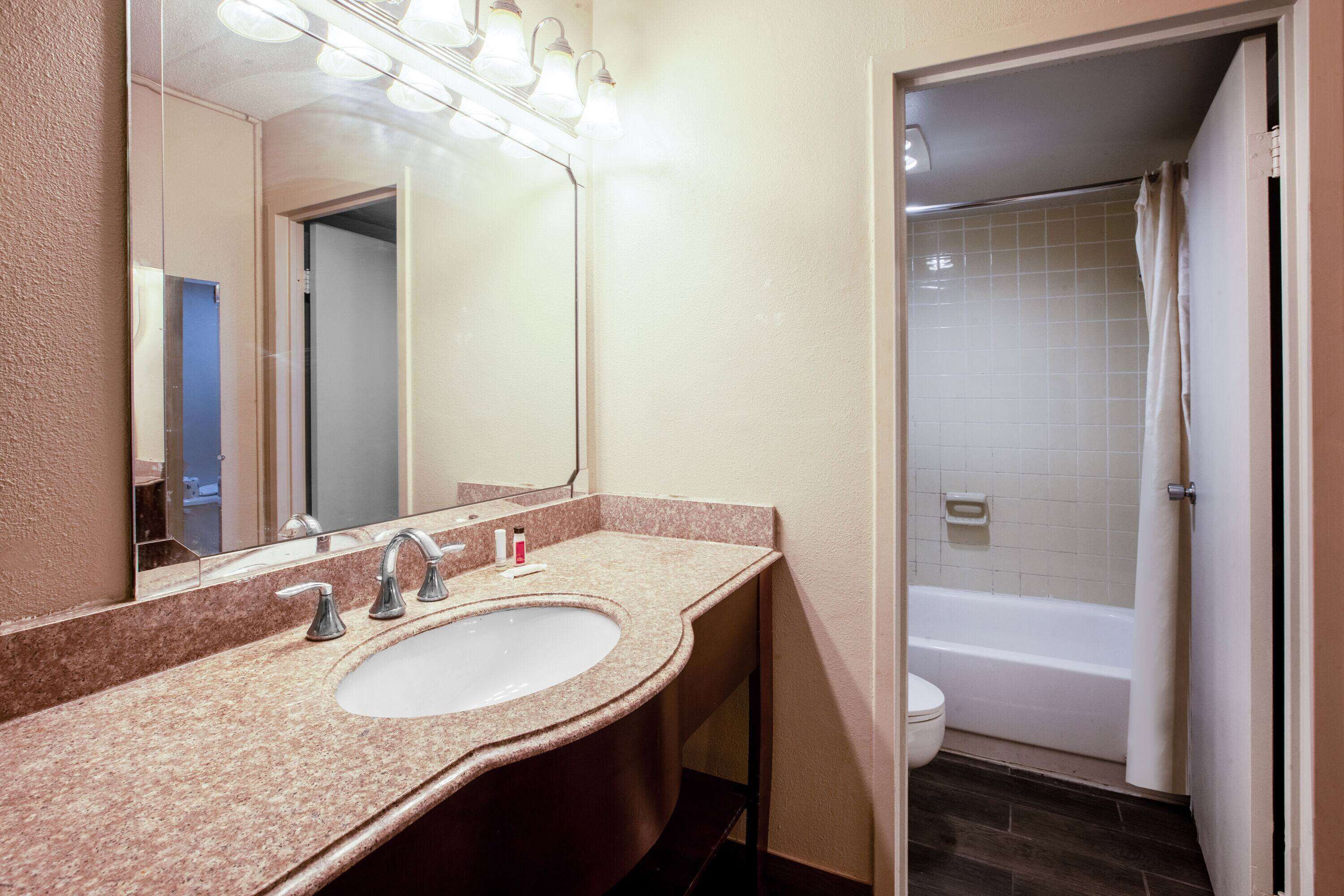 A bathroom with a sink, mirror, and shower.