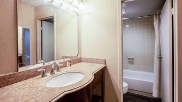A bathroom with a sink, mirror, and shower.