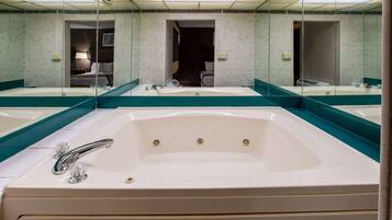 A large, white bathtub with a single faucet and three holes, surrounded by a mirror and teal-colored tiles.