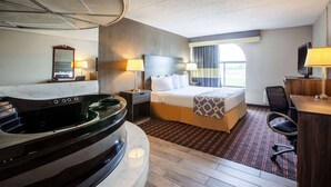 Een hotelkamer met een bed, een bureau, een stoel, een televisie, een lamp, een spiegel en een bad.