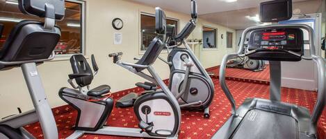 Un gimnasio con cintas de correr, elípticas y bicicletas estáticas.