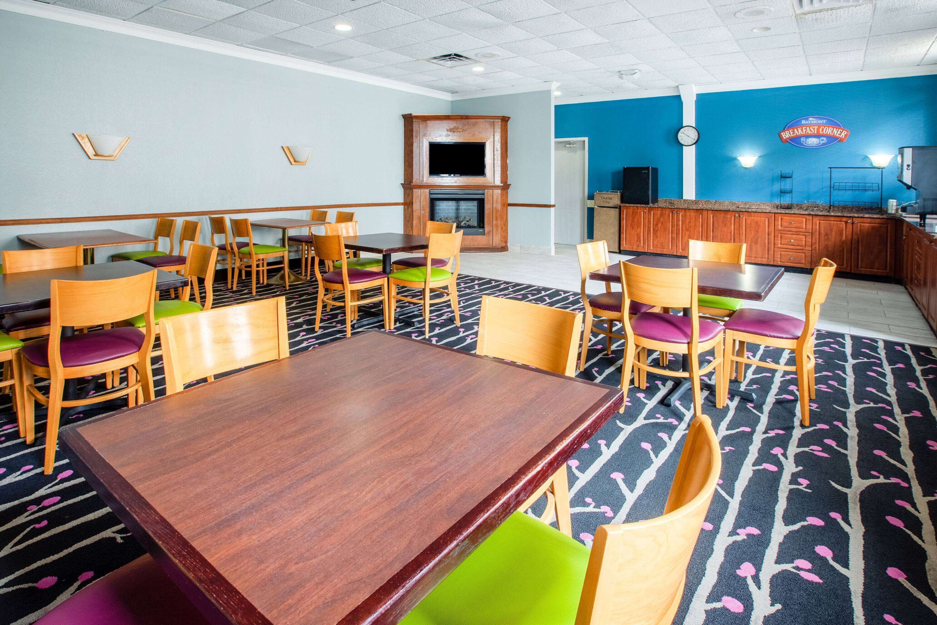 Un restaurante con mesas y sillas de madera, un televisor en la pared y un reloj.