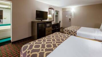 A hotel room with two beds, a desk with a television, a mirror, and a wardrobe.