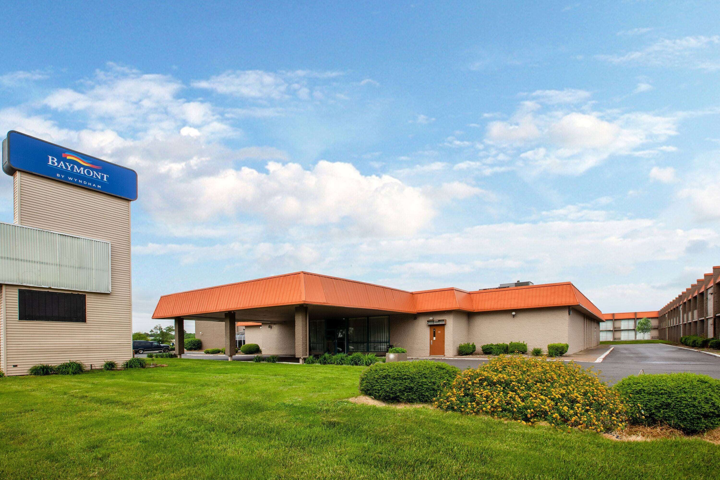A Baymont by Wyndham hotel with a red roof, beige exterior, and a parking lot.