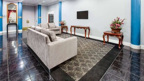 Een hal met een bank, een spiegel, een televisie en twee bijzettafels met bloemdecoraties.