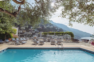 Una piscina al aire libre, sombrillas, sillones reclinables de piscina