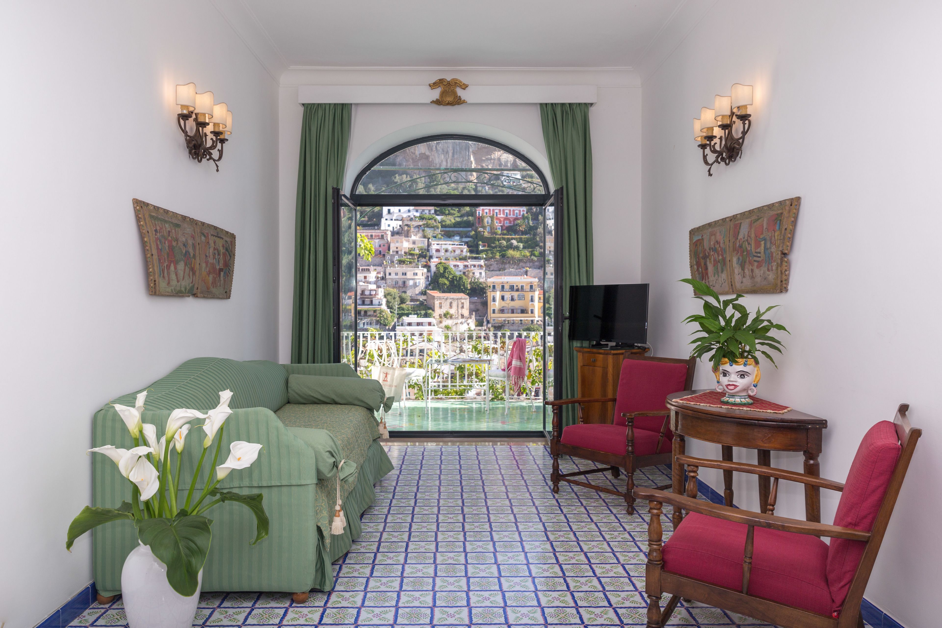 A room with a green sofa, a red chair, a small table with a plant, and a TV.