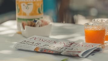 A table with a newspaper, a glass of orange juice, and a container of snacks.