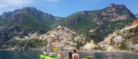 A group of people kayaking on a clear day with a mountainous backdrop.