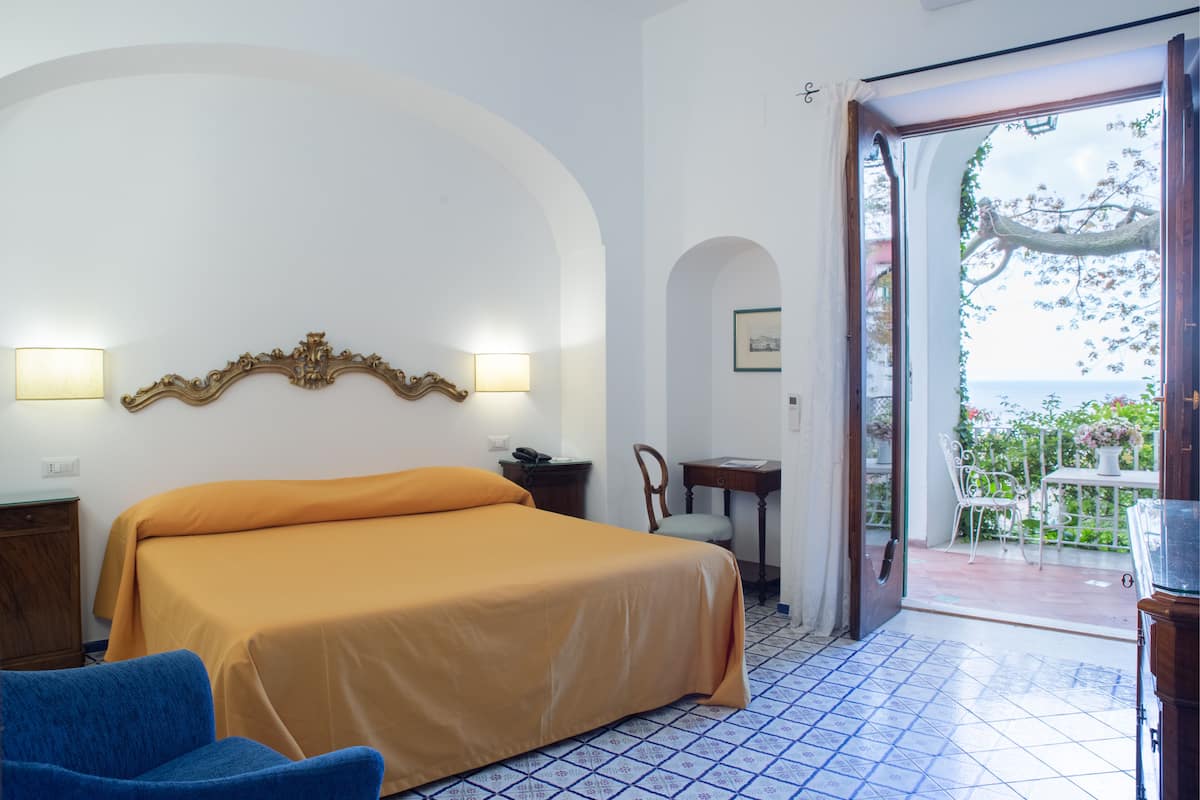 Un dormitorio con cama, una silla, un escritorio y vistas al exterior.