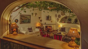 A cozy living room with a fireplace, comfortable seating, and a view through an arched window. - Poseidon Hotel (Positano)