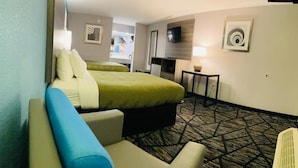 Ett hotellrum med en säng, ett skrivbord, en stol, en tv och en lampa.