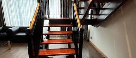 Een houten trap met zwarte leuningen en een handrail, die naar een verdieping leidt.