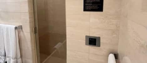 A modern bathroom with a glass shower enclosure, a black bathtub, and a towel rack.