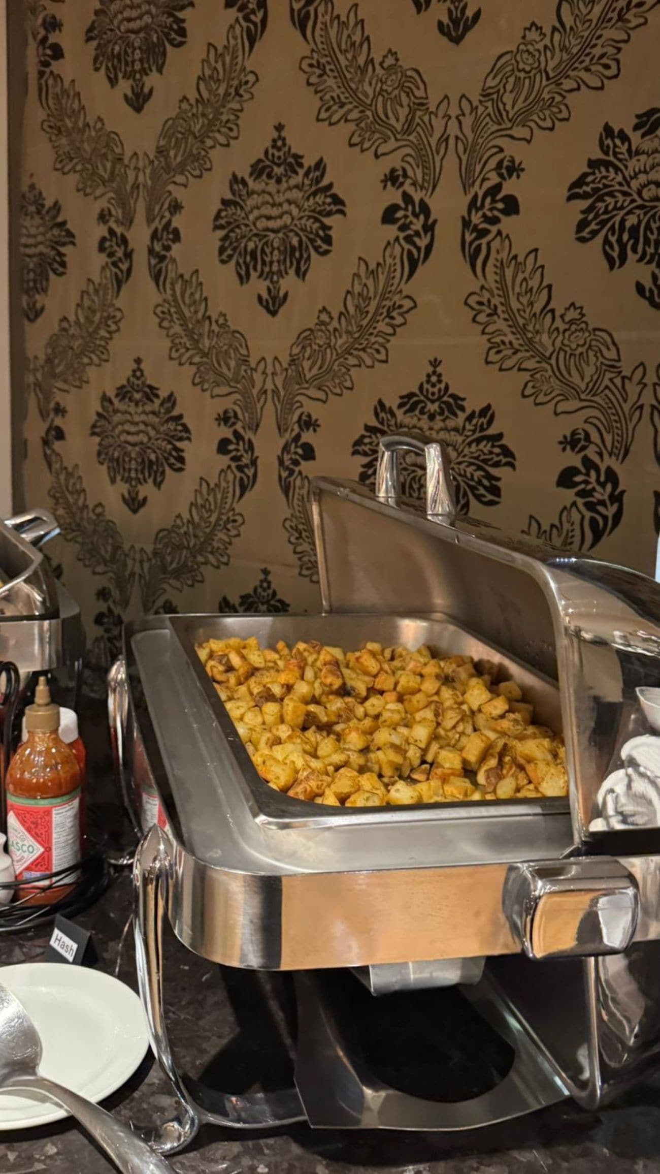 Un buffet con una varietà di piatti, tra cui patate arrosto e altri cibi pronti.
