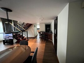 Un intérieur moderne avec une table à manger en bois, des chaises, un escalier et un coin cuisine.