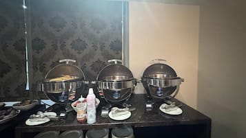 Montaje de bufé con tres grandes fuentes etiquetadas como “Bacon”, “Salchicha” y “Cerdo”. También hay condimentos y utensilios sobre la mesa.