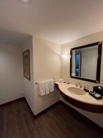 Un baño con lavabo, espejo, toallero y un cuadro en la pared.