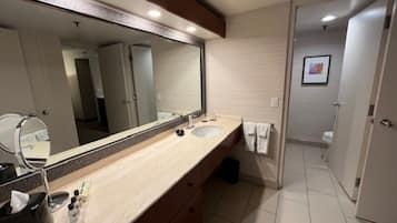 Un baño moderno con un espejo grande, un lavamanos y un inodoro.