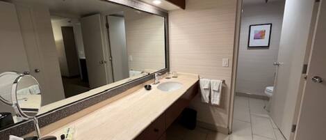 A modern bathroom with a large mirror, a sink, and a toilet.
