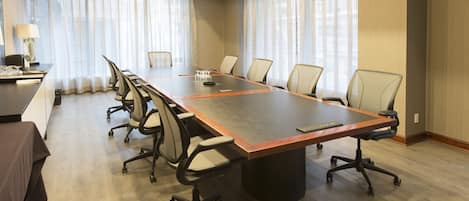A conference room with a long table, chairs, and a lamp.