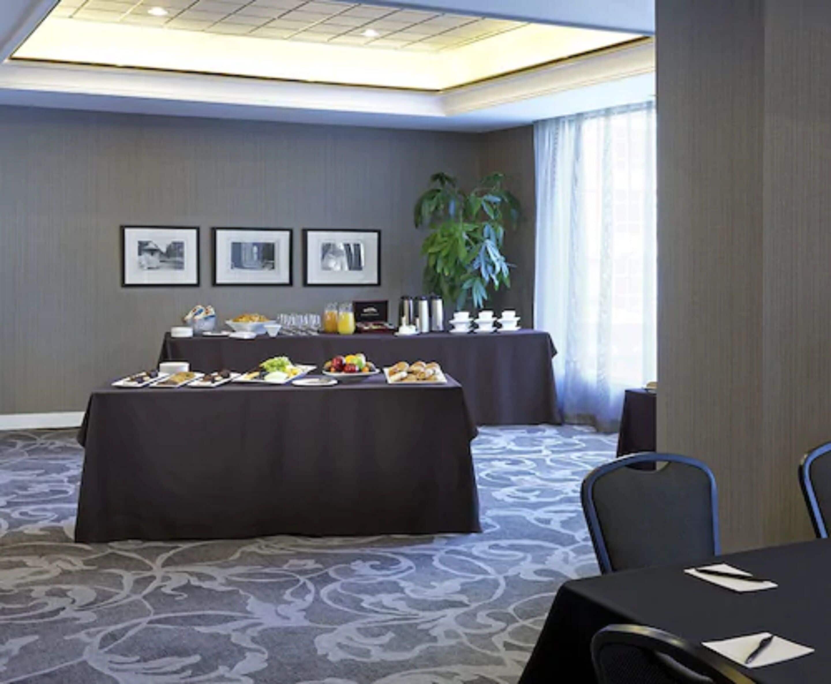 A conference room with a long table set for a meeting, a smaller table with a buffet, and framed pictures on the wall.