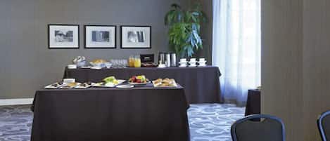 A conference room with a long table set for a meeting, a smaller table with a buffet, and framed pictures on the wall.