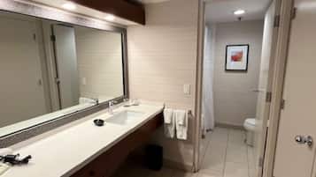 Un baño moderno con un espejo grande, un lavamanos y un inodoro.