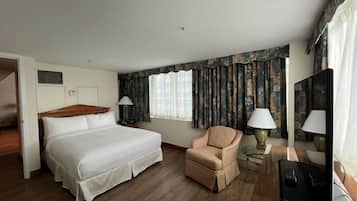 Hotelkamer met een groot bed, een stoel, een bureau met een computer en een raam met gordijnen.