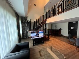 Een ruime woonkamer met een grote flatscreen televisie, een trap en een eethoek.