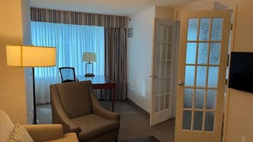 Une chambre d’hôtel équipée d’un canapé, d’un fauteuil, d’une table à manger et d’un téléviseur.