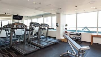 A gym with treadmills, a bench press, and a rack of dumbbells.