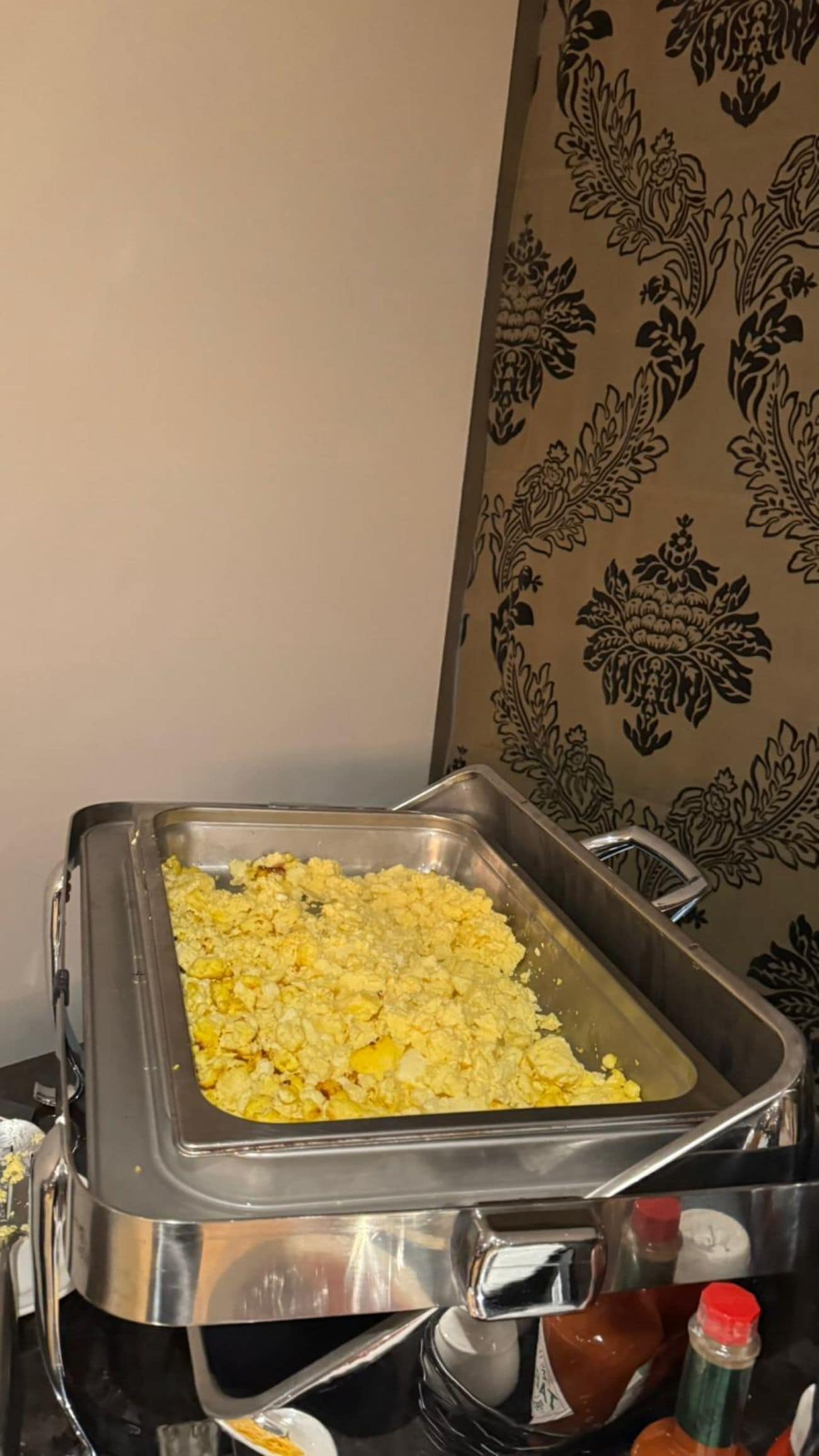 A buffet setup with scrambled eggs and condiments.