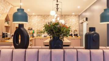 A modern kitchen with a brick backsplash, pendant lights, and a central vase with flowers.