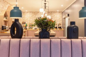 A modern kitchen with a brick backsplash, pendant lights, and a central vase with flowers.