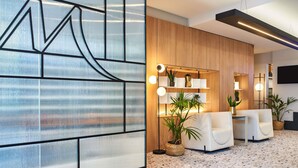 Una moderna zona de recepción con un diseño mural geométrico, un panel de madera de fondo y una sala de estar con piso de terrazzo.