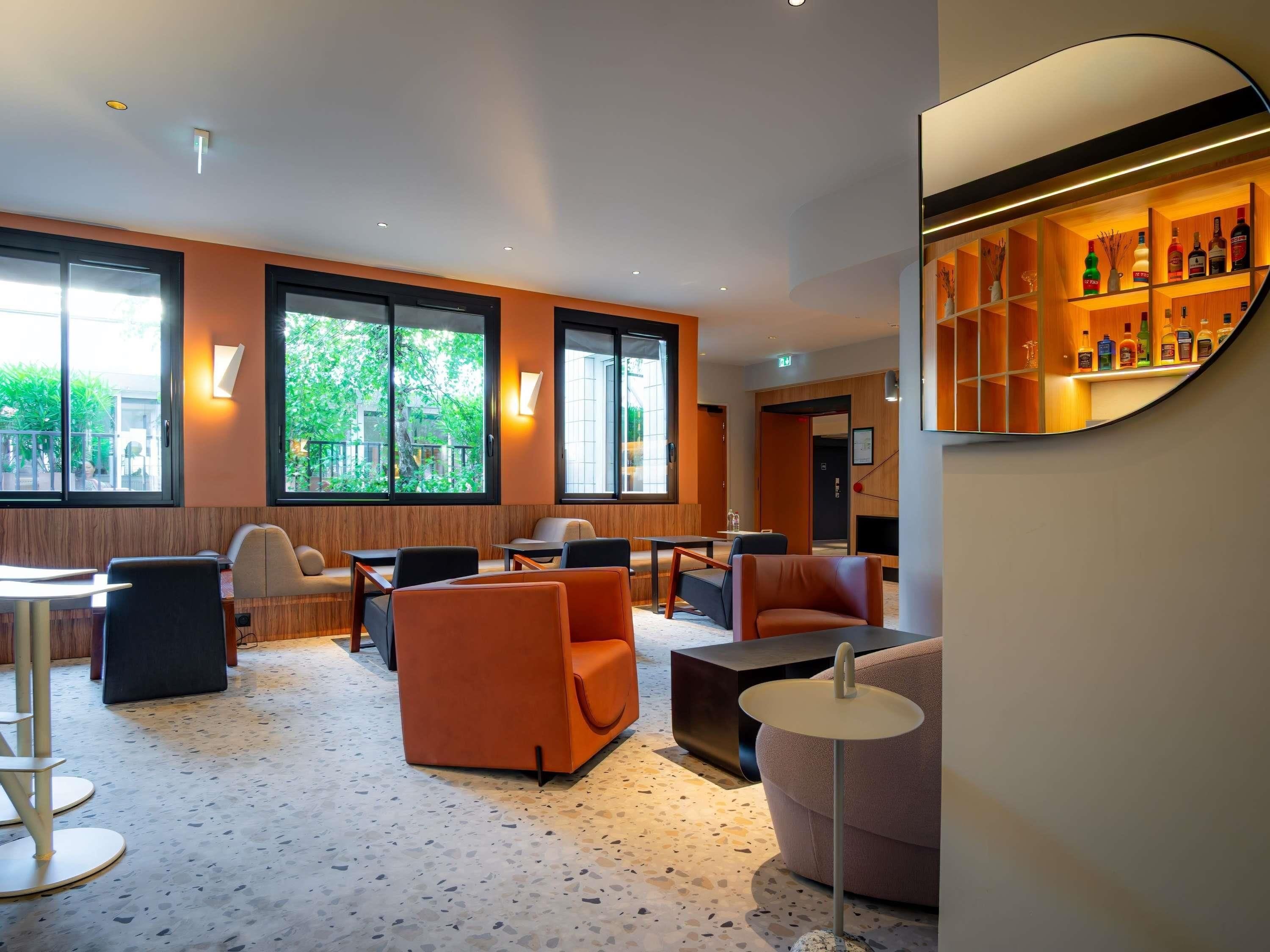 Un hall d’hôtel moderne, doté d’un espace salon, d’un bar et de grandes fenêtres.