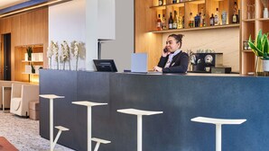 Un área de bar moderna con mostrador, taburetes y una variedad de botellas y vasos.