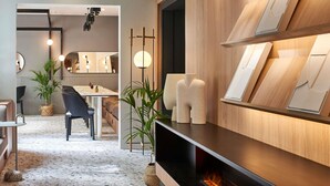 Un interior moderno con una pared de madera decorada con cuadros enmarcados, una chimenea con fuego encendido y una zona de comedor con mesa y sillas.